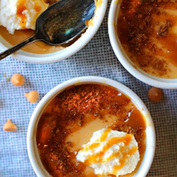 three stoneware ramekins filled with butterscotch pudding topped with whipped cream