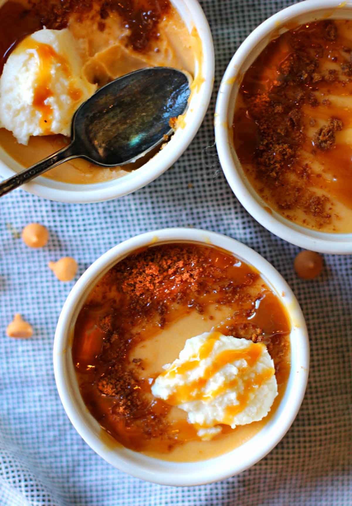 three stoneware ramekins filled with butterscotch pudding topped with whipped cream