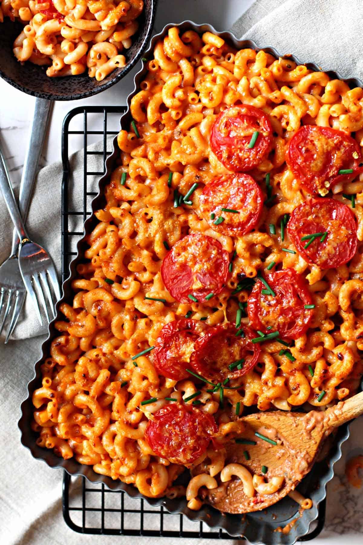 A casserole dish filled with Mexican Macaroni and Cheese topped with sliced tomatoes
