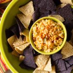Mexican Street Corn Dip served with yellow and blue corn tortilla chips.