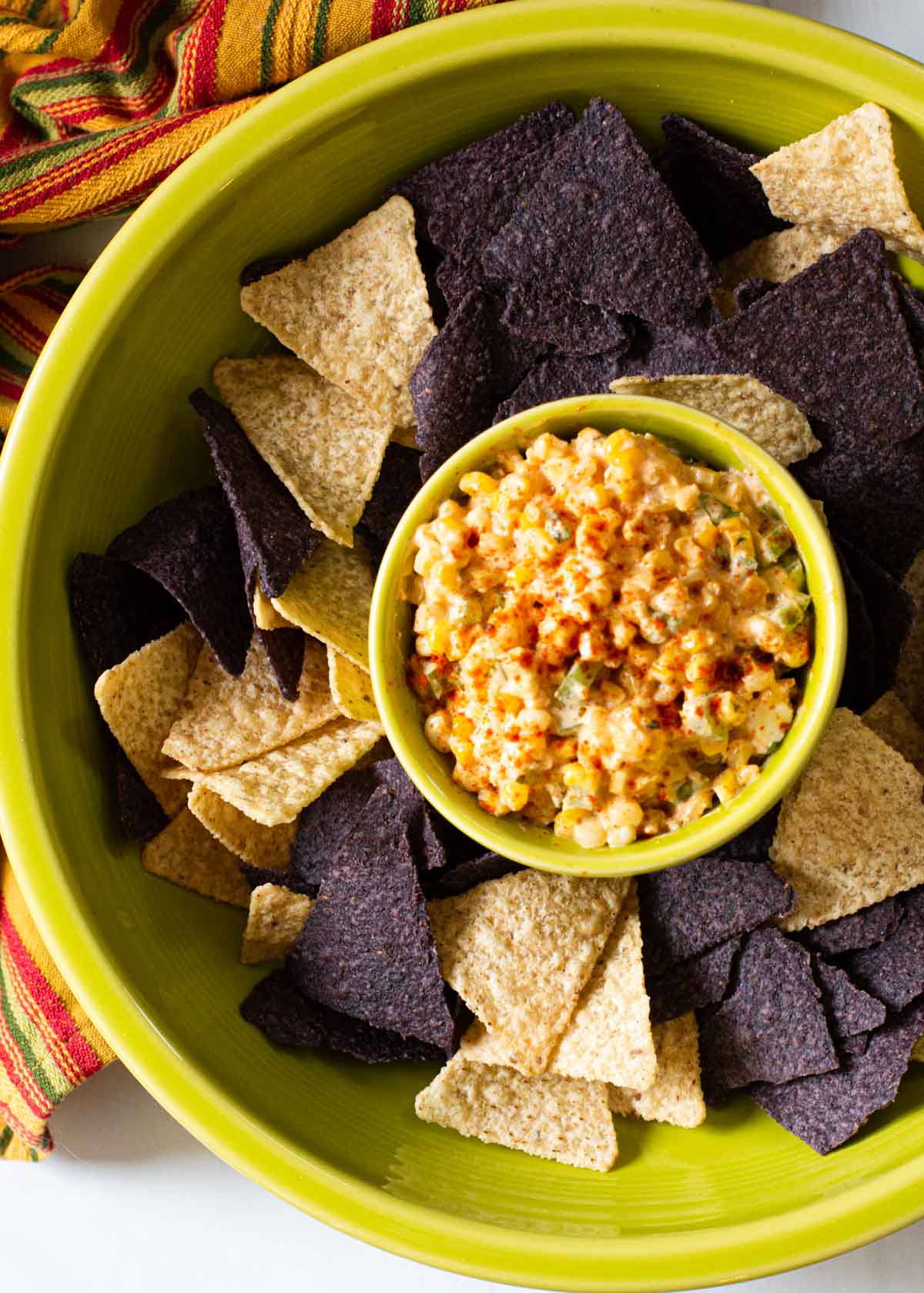 Mexican Street Corn Dip served with yellow and blue corn tortilla chips.