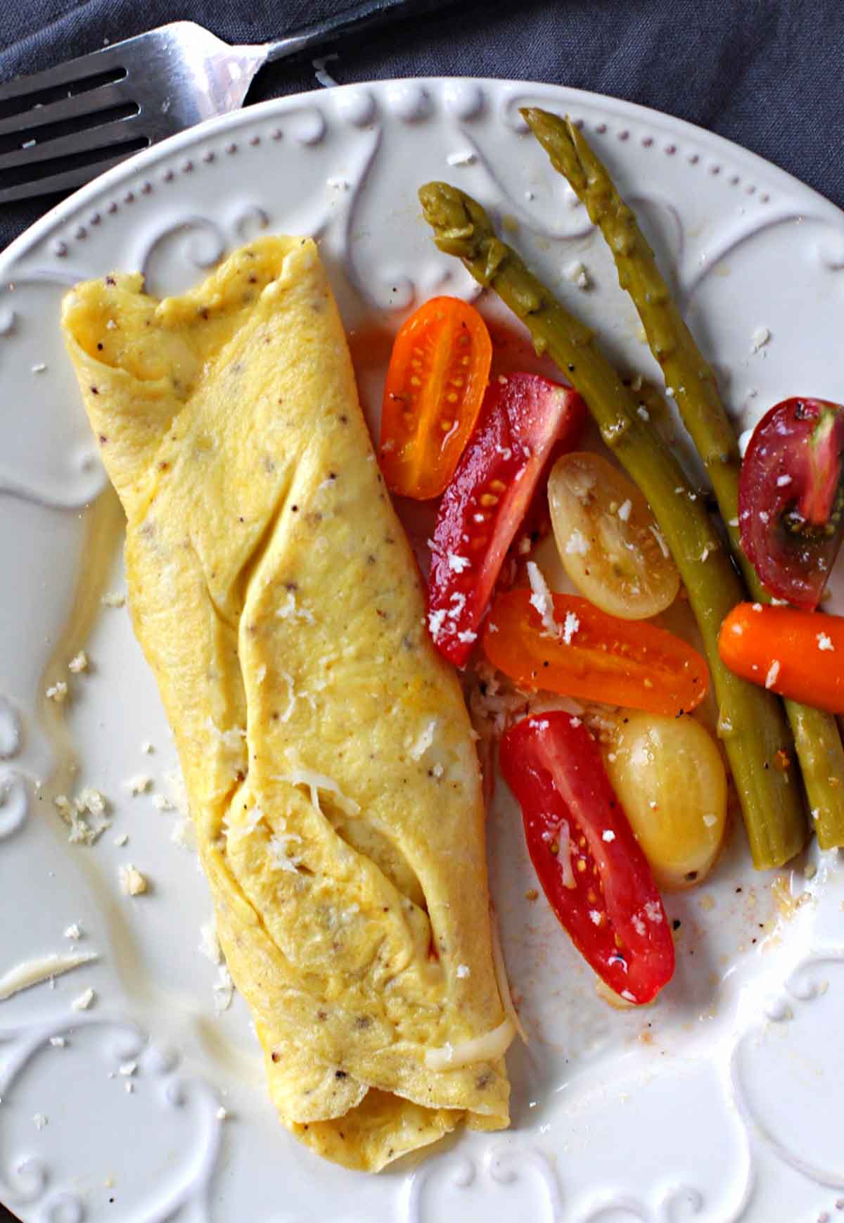 Omelette au fromage, cheese omelette served with sliced petite tomatoes and pickled asparagus