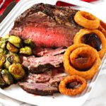 Boneless prime rib roast cooked and served with brussels sprouts and onion rings