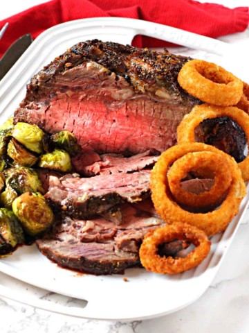 Boneless prime rib roast cooked and served with brussels sprouts and onion rings