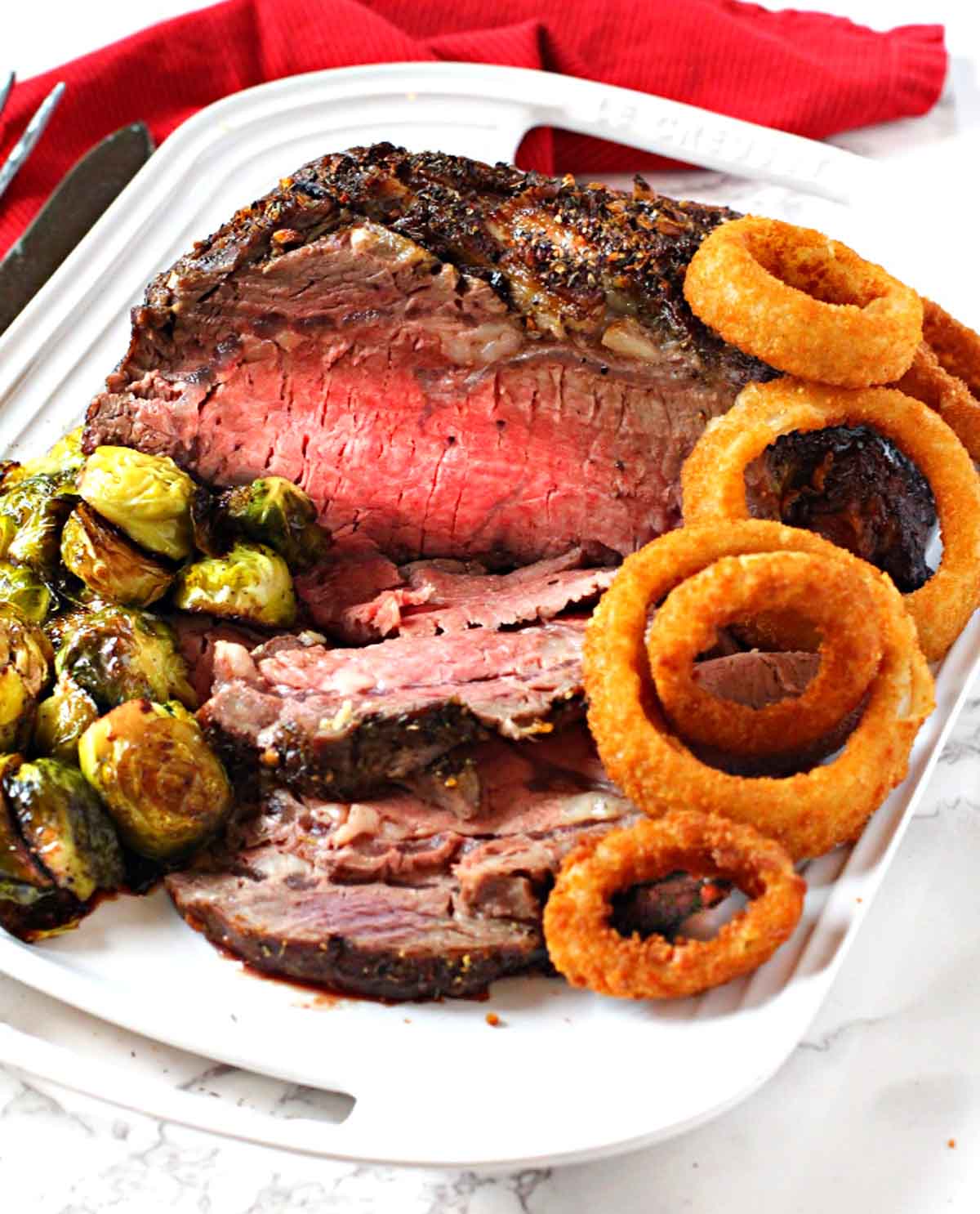 Boneless prime rib roast cooked and served with brussels sprouts and onion rings