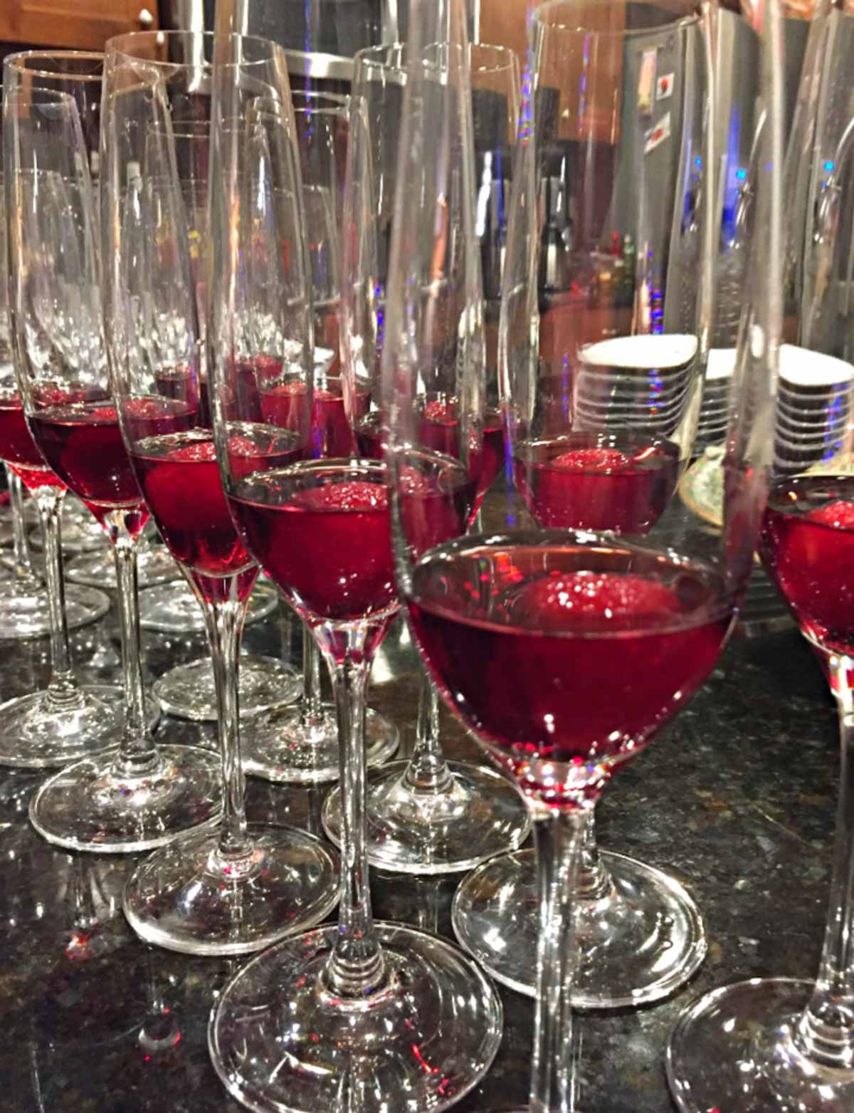 Champaign glasses lined up with chambord and raspberries, for a make ahead christmas cocktail