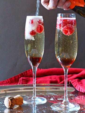Prosecco Christmas Cocktail made with Chambord Liqueur and fresh raspberries. Served in Champagne flutes.