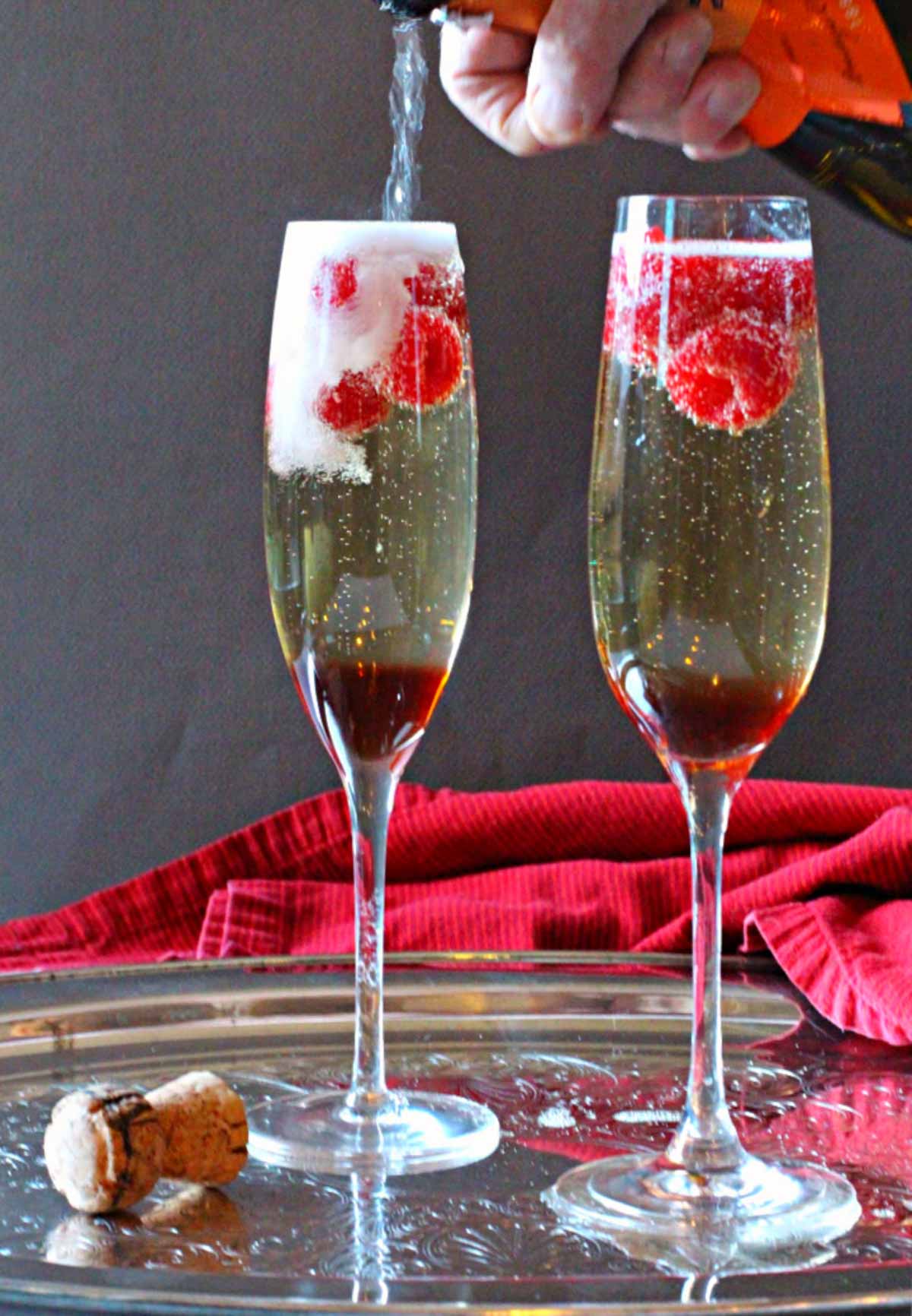 Prosecco Christmas Cocktail made with Chambord Liqueur and fresh raspberries. Served in Champagne flutes.