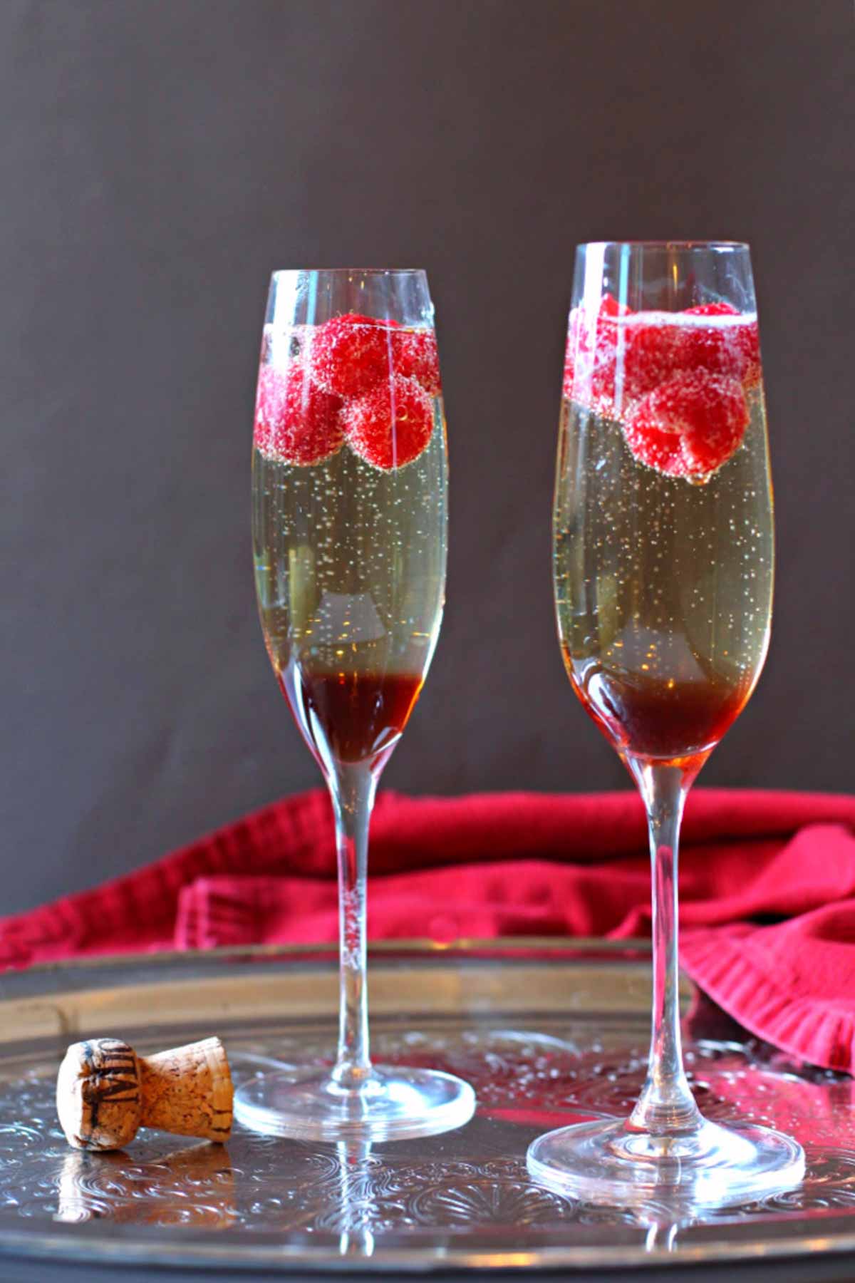 Raspberry Chambord Prosecco cocktail served in two champagne glasses with raspberries.