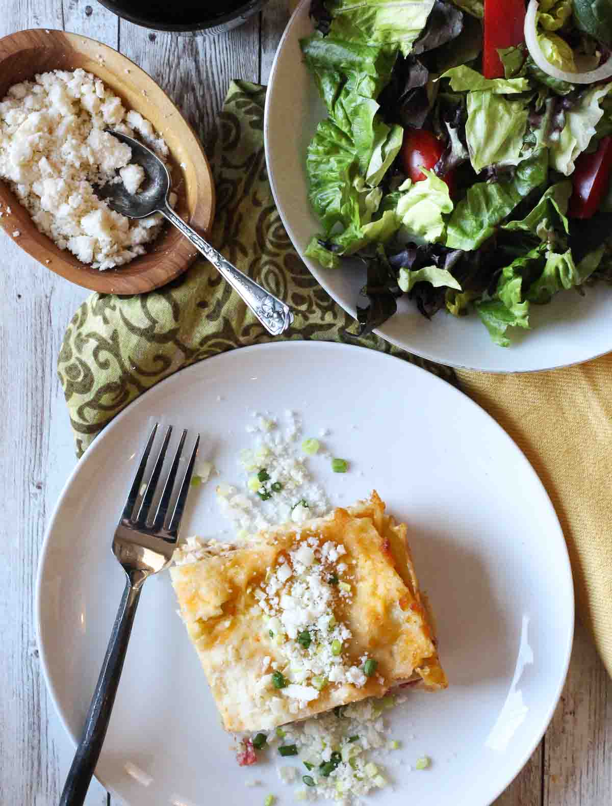 A slice of green chile chicken lasagna with a green salad.