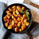 Cubed potatoes cooked in a cast iron skillet with rosemary