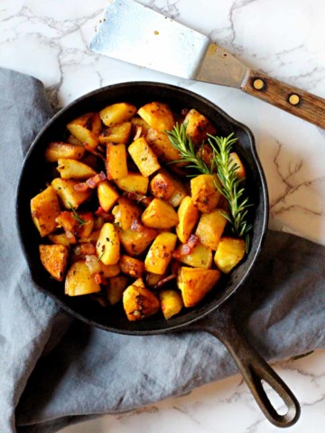 Cubed potatoes cooked in a cast iron skillet with rosemary