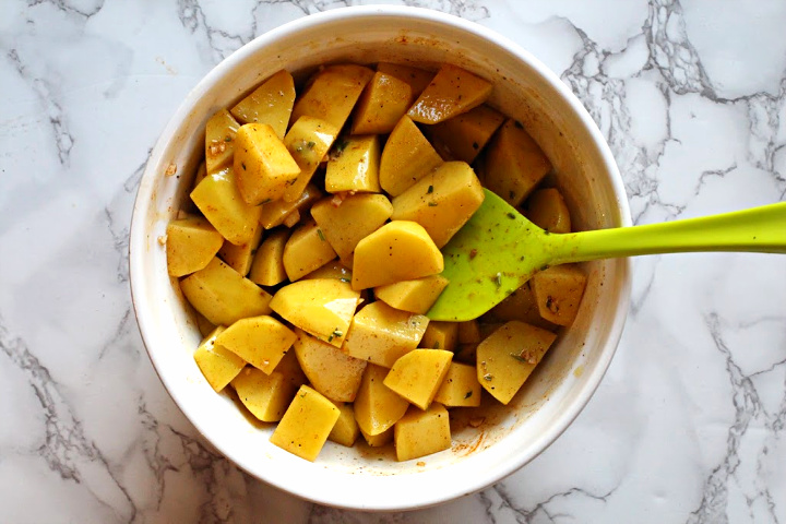 Cubed yukon gold potatoes coated with seasonings for cask iron skillet oven roasted potatoes