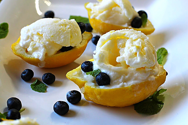 Frozen lemon milk and cream served in a hollowed out lemon shell garnished with blueberries and mint leaves