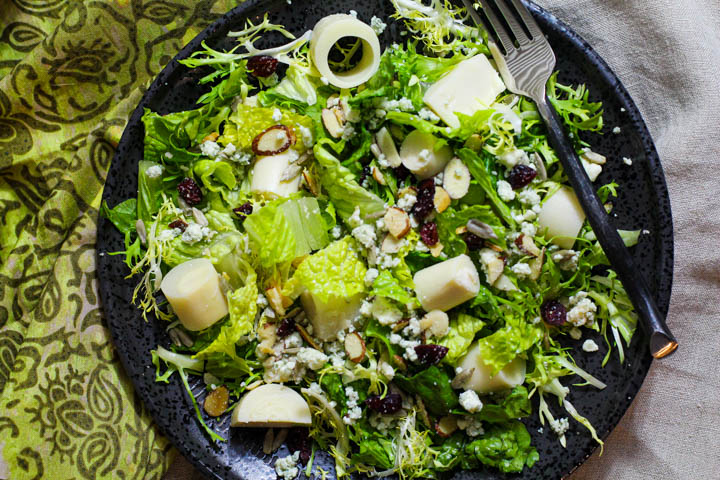 Tossed salad with hearts of palm, dried cranberries, blue cheese dressing served in a World Market rustic black bowl.