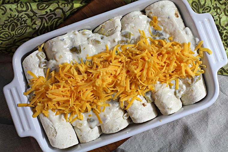 Avocado and scrambled egg breakfast burritos in an oven proof casserole dish topped with shredded cheese