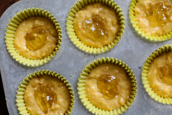 Corn muffins in a muffin tin with jalapeno jelly in the center