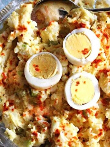 Old fashioned potato salad with olives, topped with sliced hard boiled eggs.
