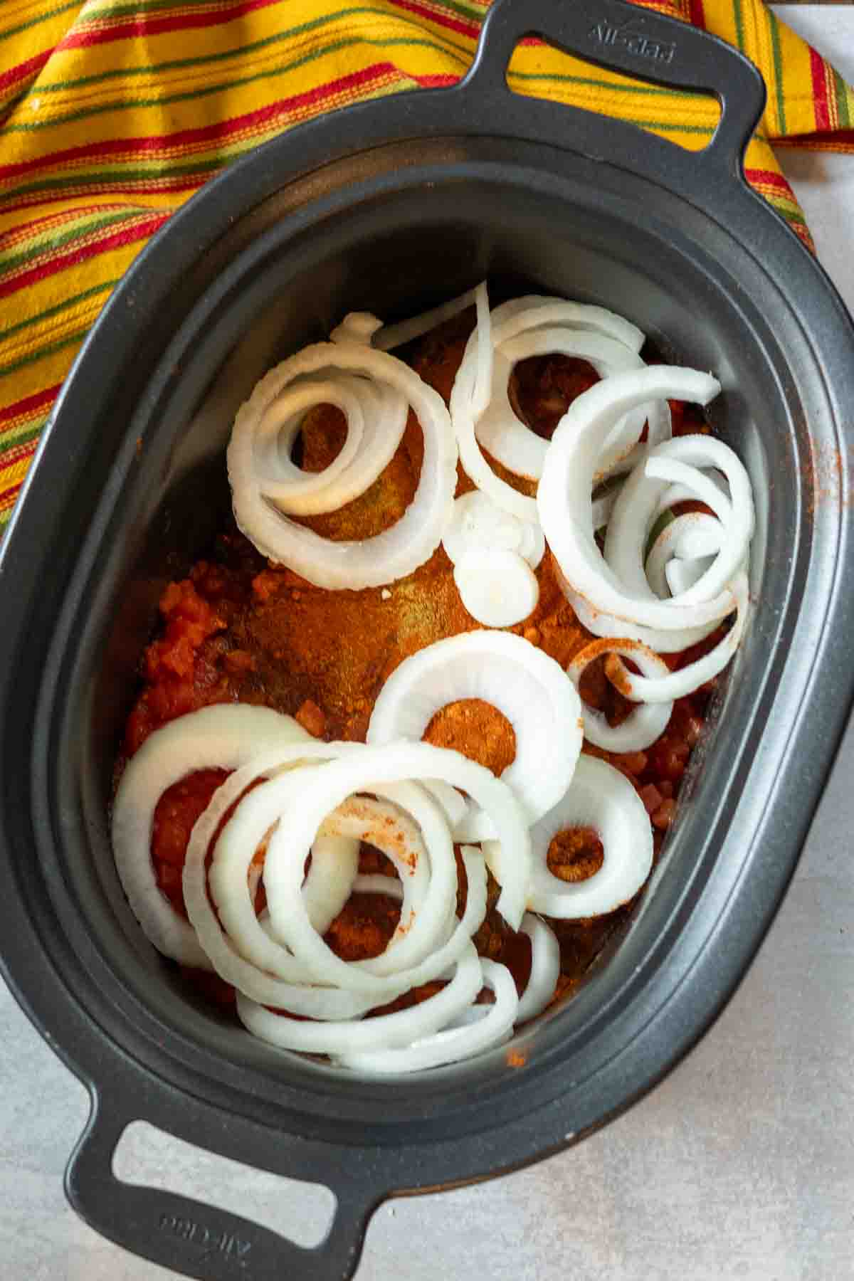 Cooking a chuck roast, spices and vegetables in a crock pot to make roast beef tacos.
