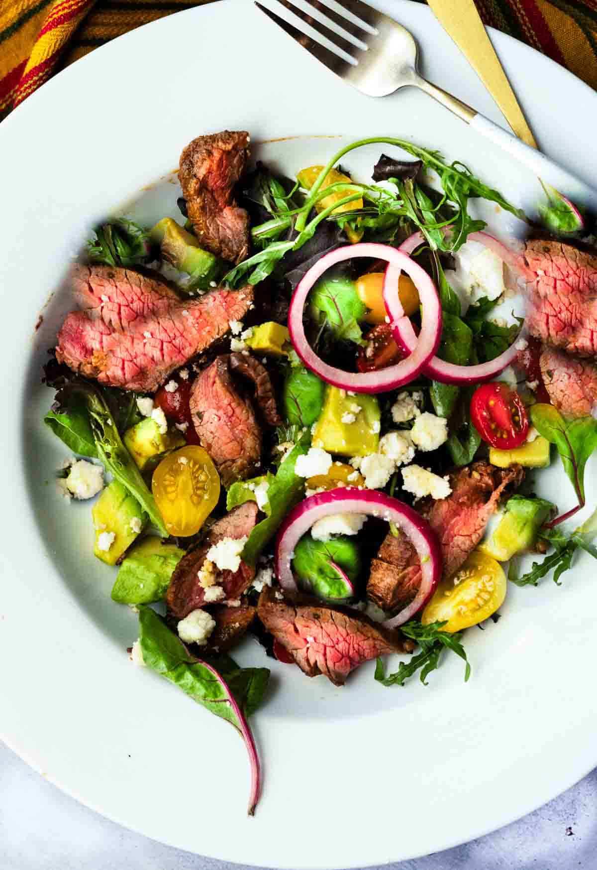 Chipotle honey glazed skirt steak salad with avocado, tomatoes and greens.