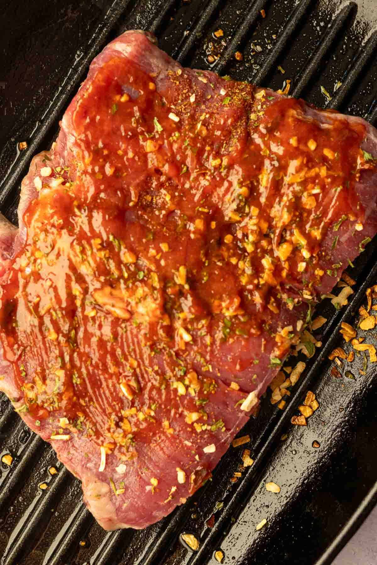 Applying honey chipotle glaze to skirt steak while cooking.