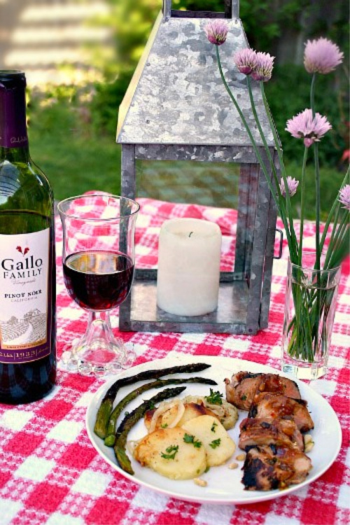 Mexican pork tenderloin served on a picnic table cloth with potatoes and asparagus.