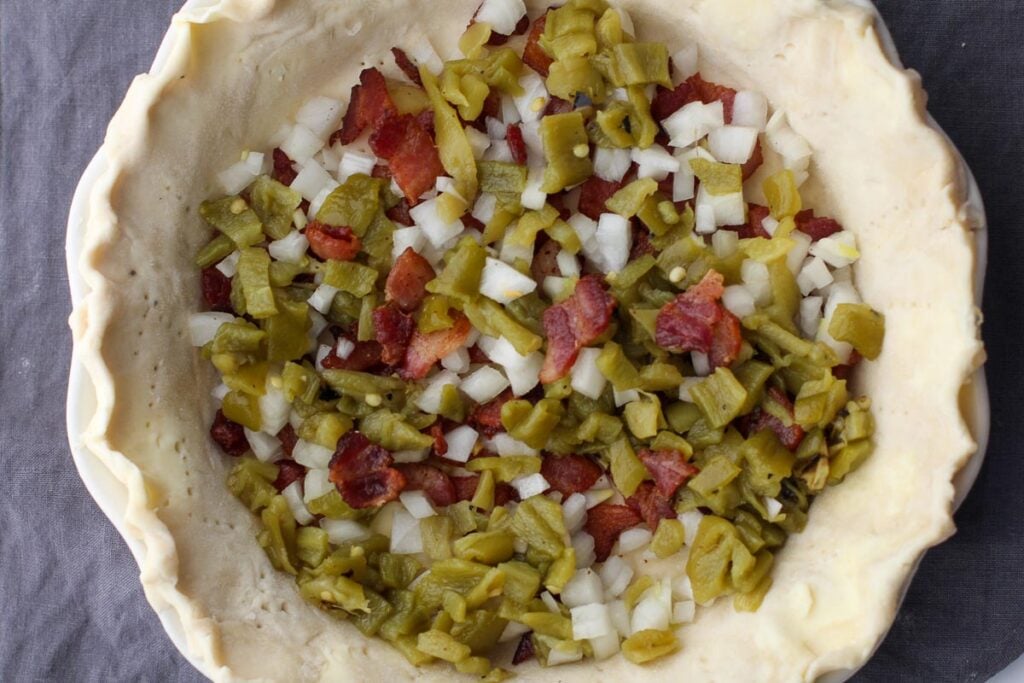 green chile, bacon bits and chopped onion in a pie crust for bacon chile quiche