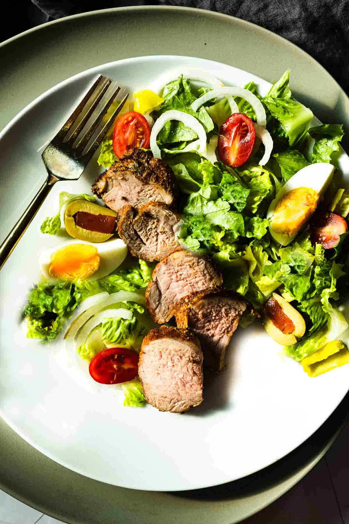 Slices of baked pork tenderloin served with a tossed salad.