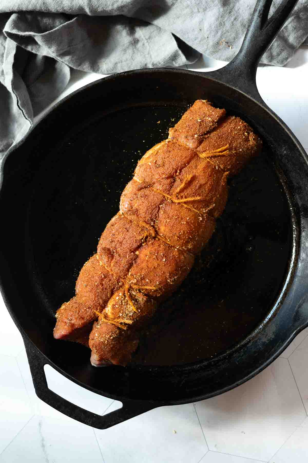 Oven baking a pork tenderloin in a cast iron skillet.