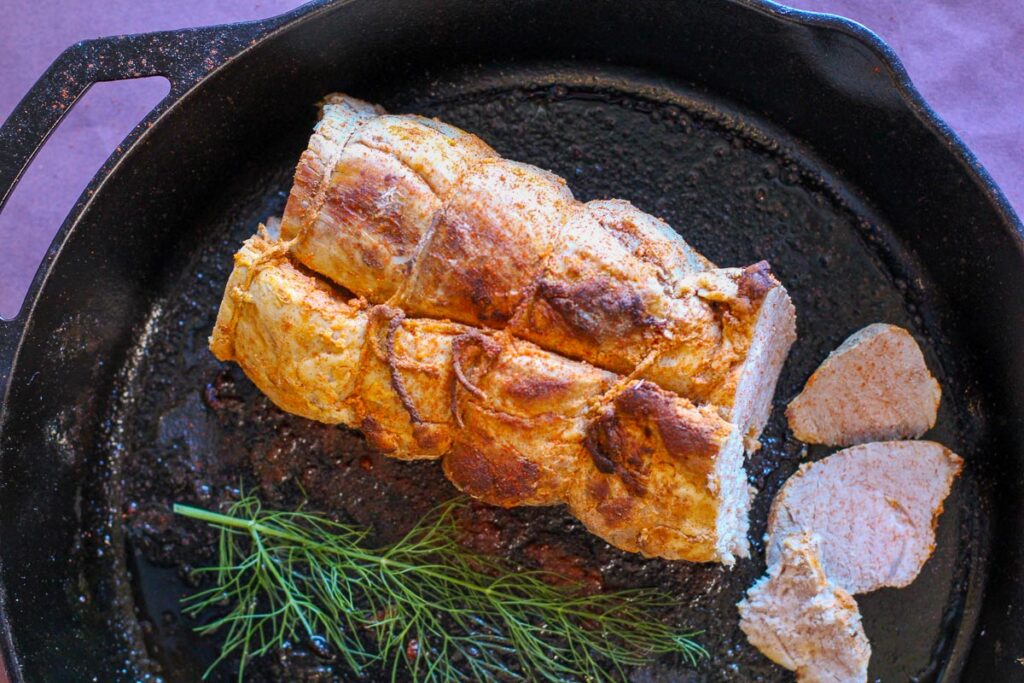 Pork Tenderloin tied with twine and cooked in a cast iron skillet