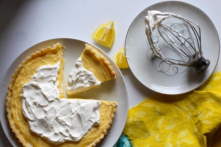 A lemon dessert topped with whipped cream and Le Creuset whipping tool on a plate