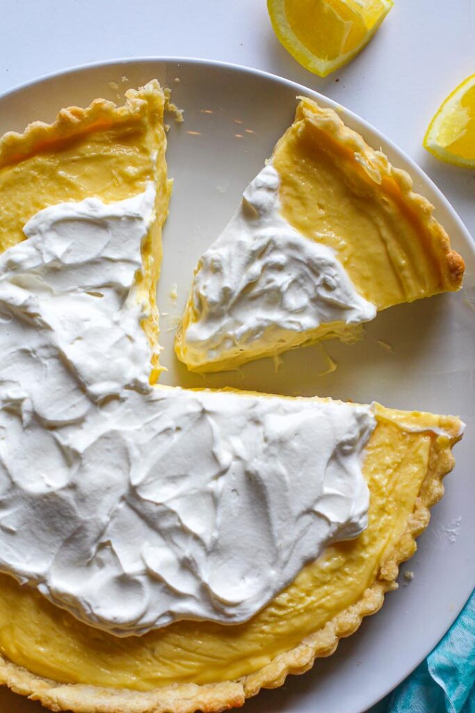 No Bake lemon dessert tart topped with whipped cream with a slice cut out.