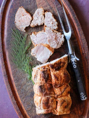 Pork tenderloin sliced on a cutting board that's been rubbed with cooking spices