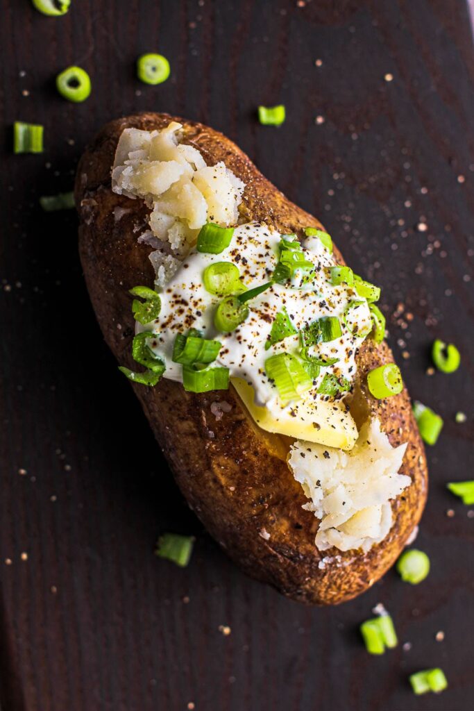 Slow Cooker Baked Potato topped with sour cream, chives and butter