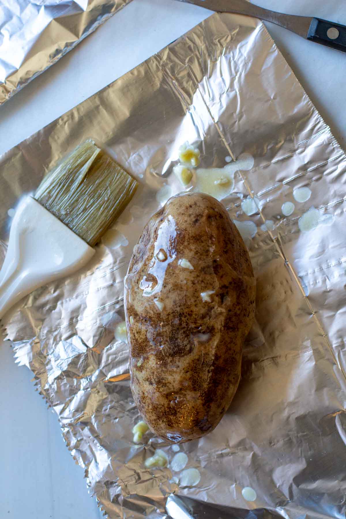 Brusing russet potatoes with garlic butter.