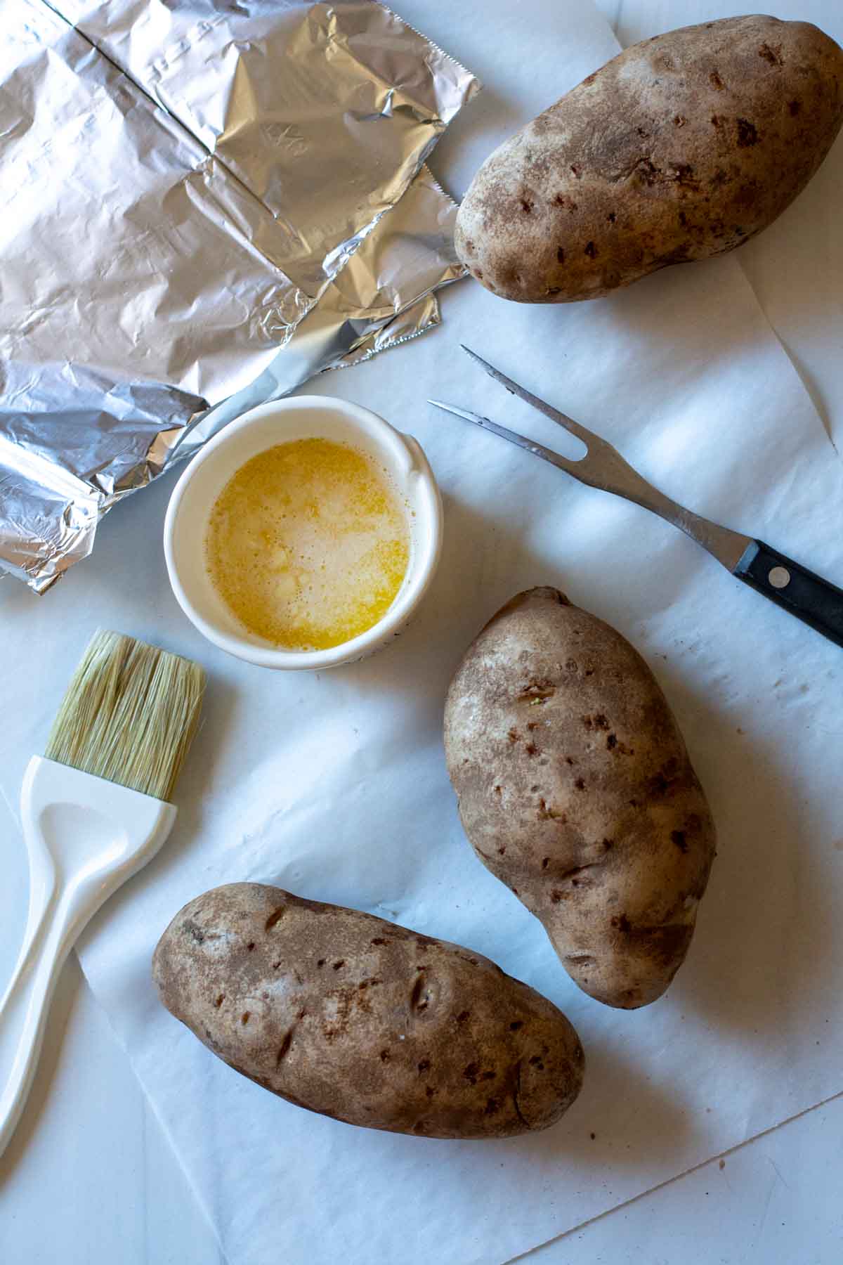 Preparing baked potatoes for slow cooker roasted potatoes.