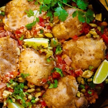Mexican chicken and rice in a cast iron skillet garnished with cilantro and green olives