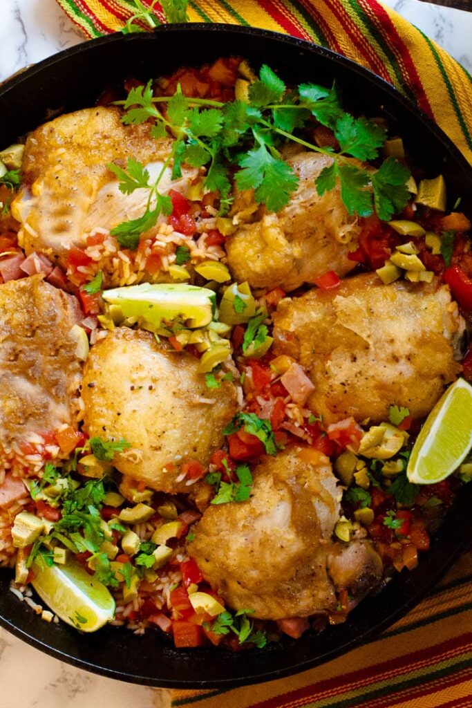 Mexican chicken and rice in a cast iron skillet garnished with cilantro and green olives