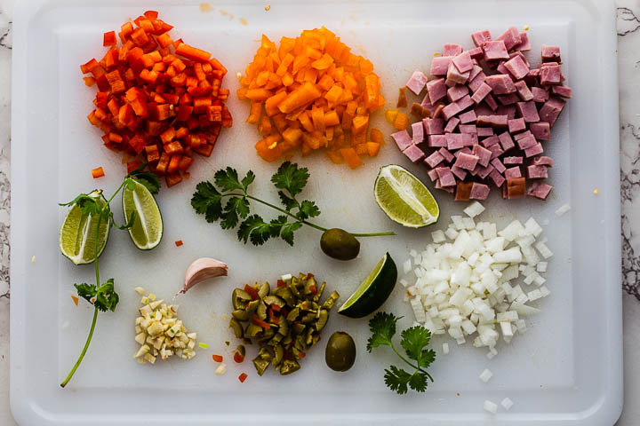 Arroz con Pollo ingredients. Chopped bell peppers, chopped ham, chopped onions, chopped green olives, chopped garlic and cilantro