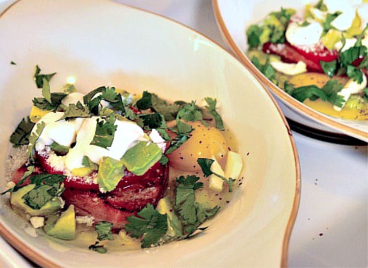 baked eggs with avocado ham tomato and sour cream served in an oven proof dish