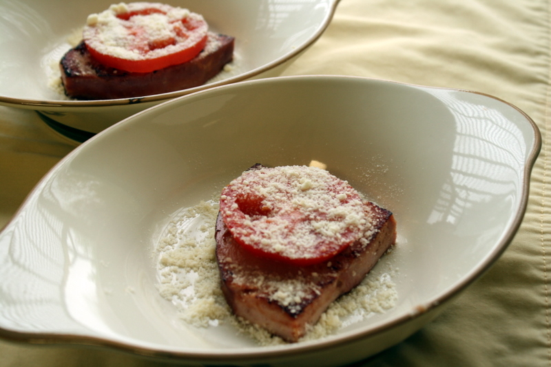 A slice of toast topped with a slice of fresh tomato and sprinkled with Parmesan cheese