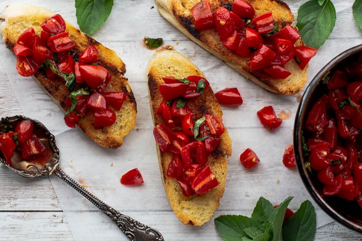 Sliced and toasted baguette topped with fresh chopped tomatoes and sprinkled with fresh slivered basil.