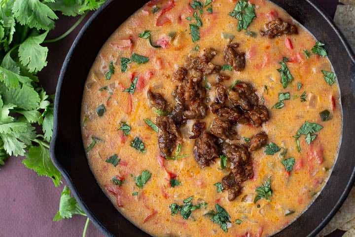 Queso fundido served in a cast iron skillet topped with cooked chorizo
