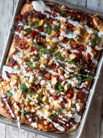BBQ chicken pizza cooked in a sheet pan with tomatoes, jalapeno, cilantro and drizzled with ranch dressing