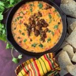 Queso fundido with tequila served in a cast iron skillet and topped with cooked chorizo