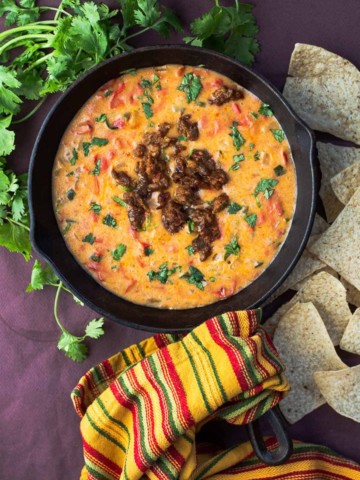 Queso fundido with tequila served in a cast iron skillet and topped with cooked chorizo