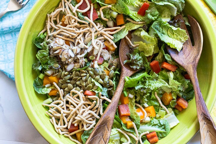 Asian lettuce salad with chow mein noodles, pepita seeds, bell pepper, and green onions.