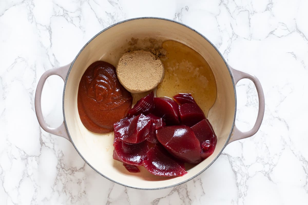 Ingredients in a dutch oven for Sriracha Cranberry Meatballs