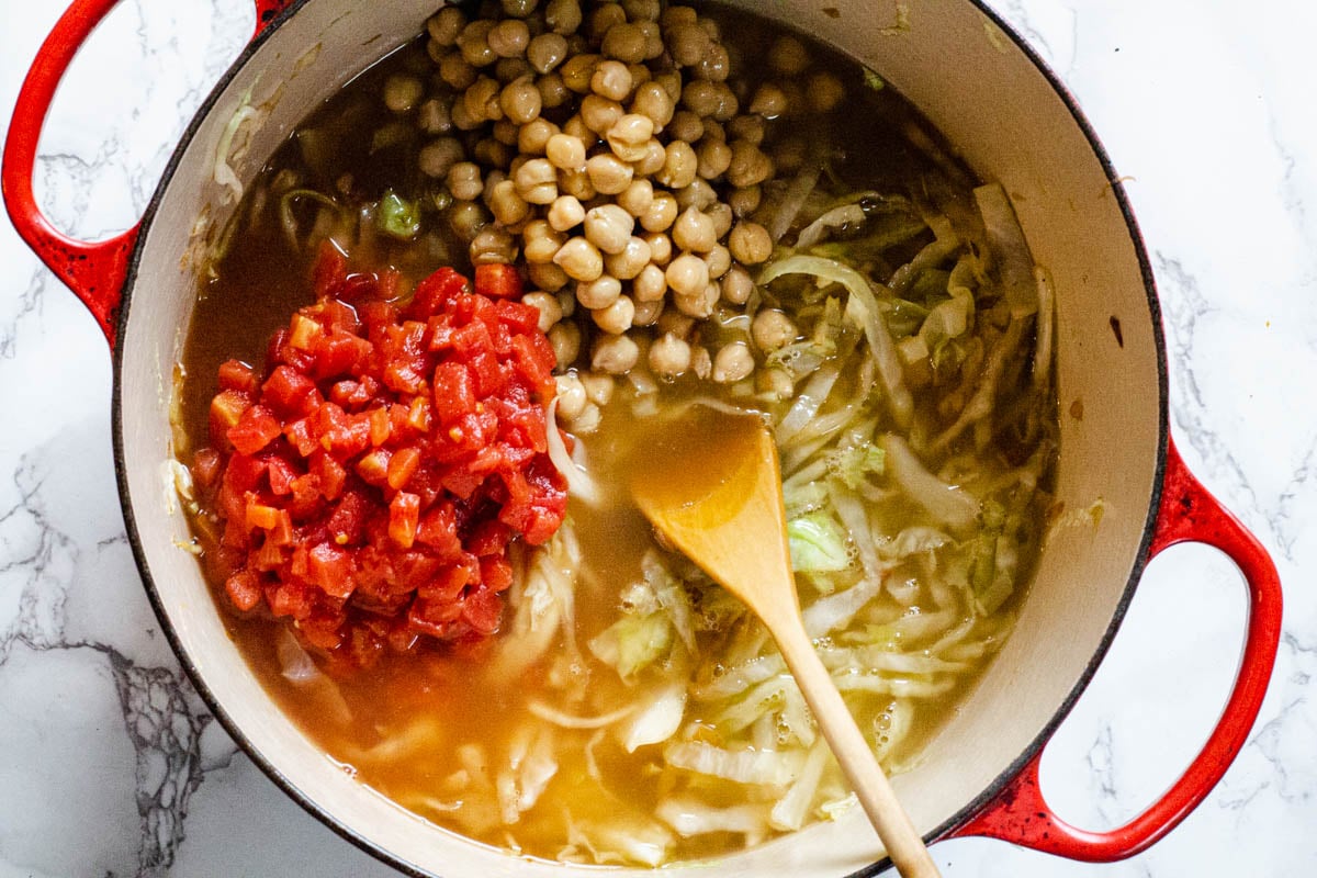 Adding Chickpeas, tomatoes and cabbage to chorizo soup.