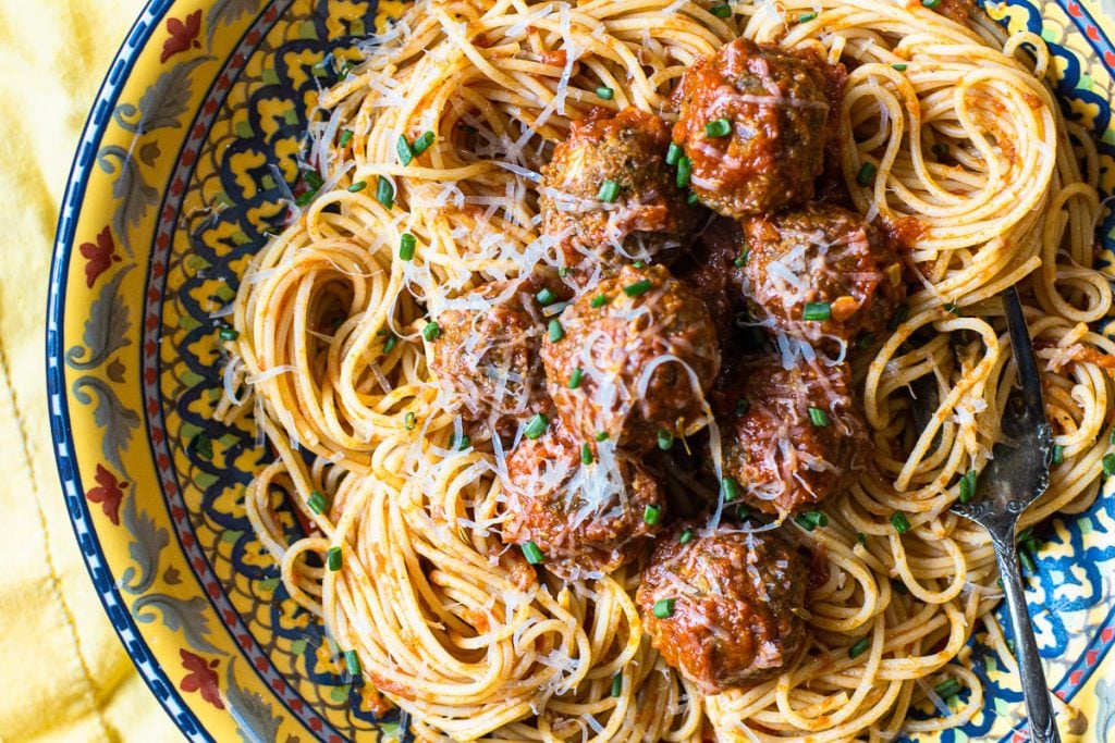 Homemade Italian Meatballs over spaghetti with red sauce, garnished with parmesan cheese and chives